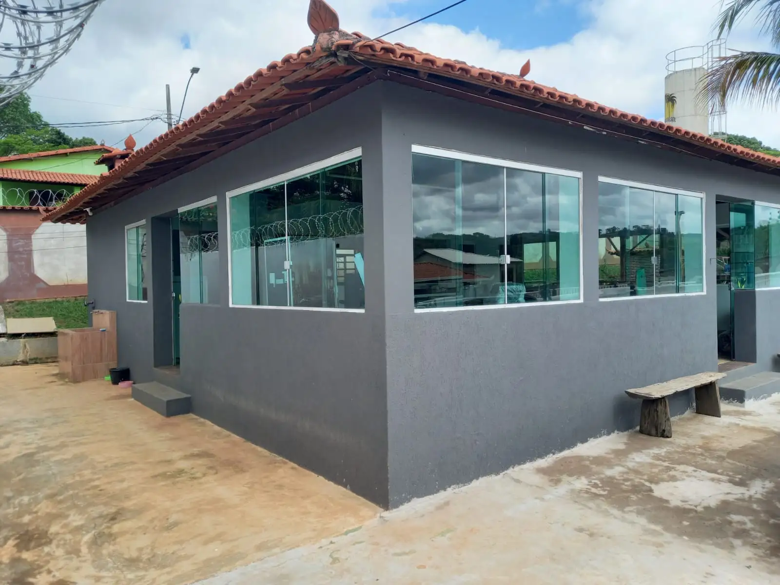 Salão com paredes de vidro e bancos na área externa.